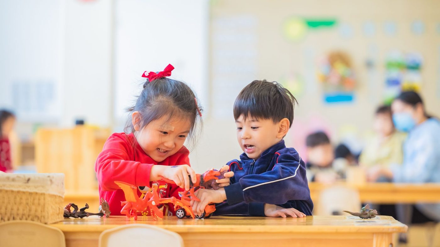 Deux enfants jouent ensemble avec de petits jouets à une table de classe