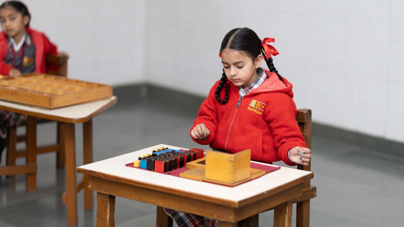 Fillette au travail sur un plateau de matériel, dans une classe Montessori