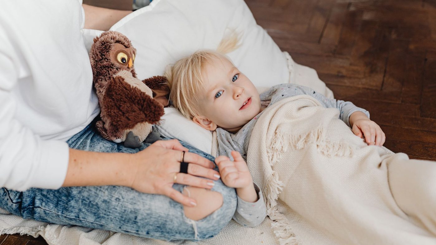 Un enfant blotti sur les genoux de sa mère, son doudou hibou contre lui