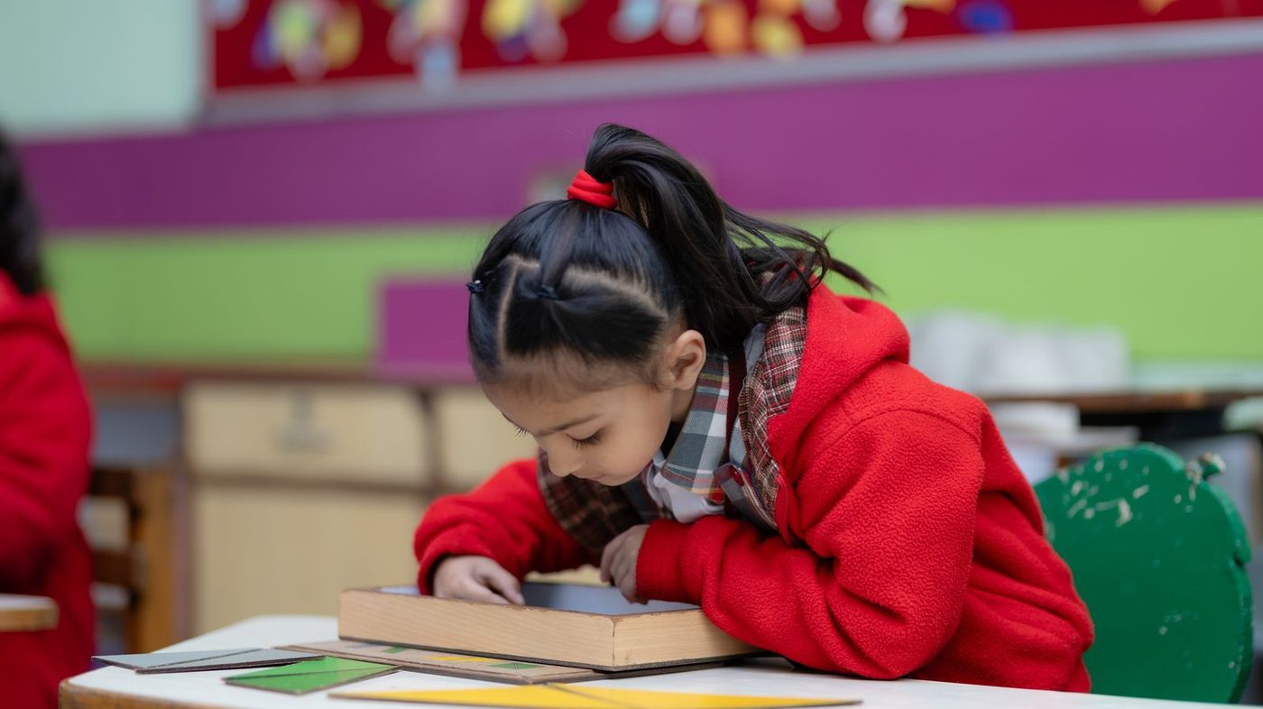 Une enfant seule à sa table, absorbée par son matériel