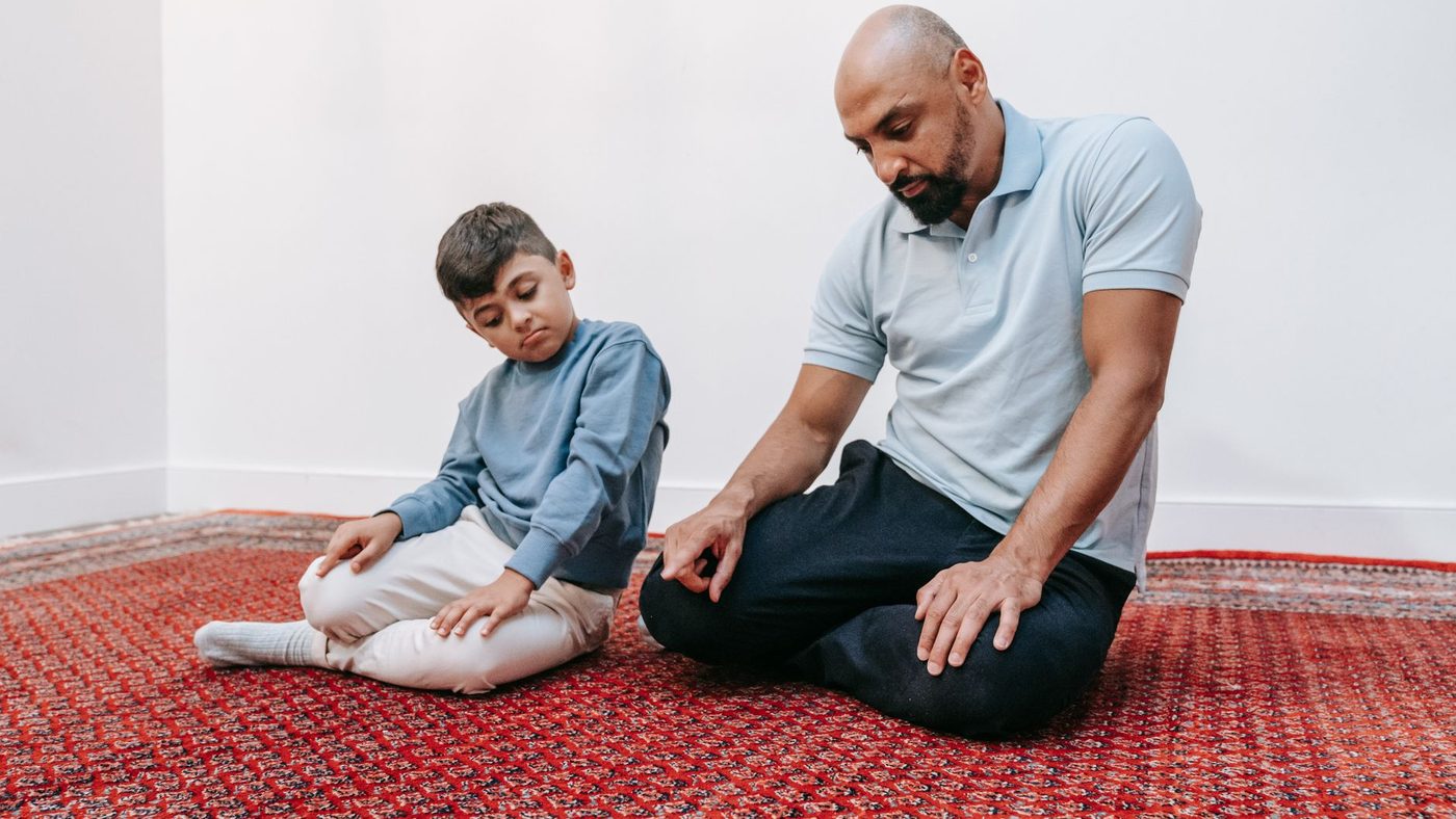 Assis sur un tapis, un père parle calmement à son fils