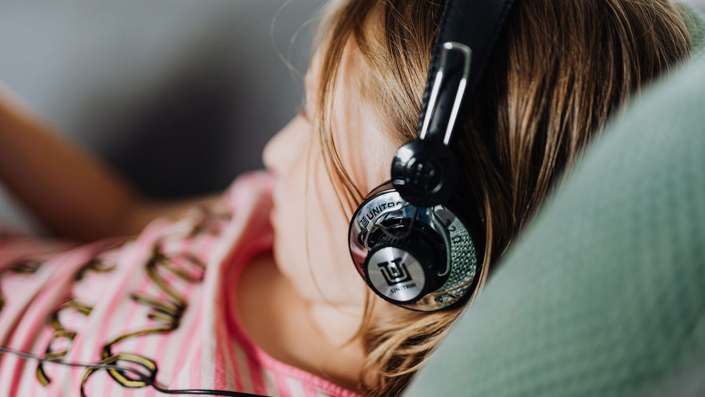 Une enfant allongée écoute une histoire avec un casque sur les oreilles