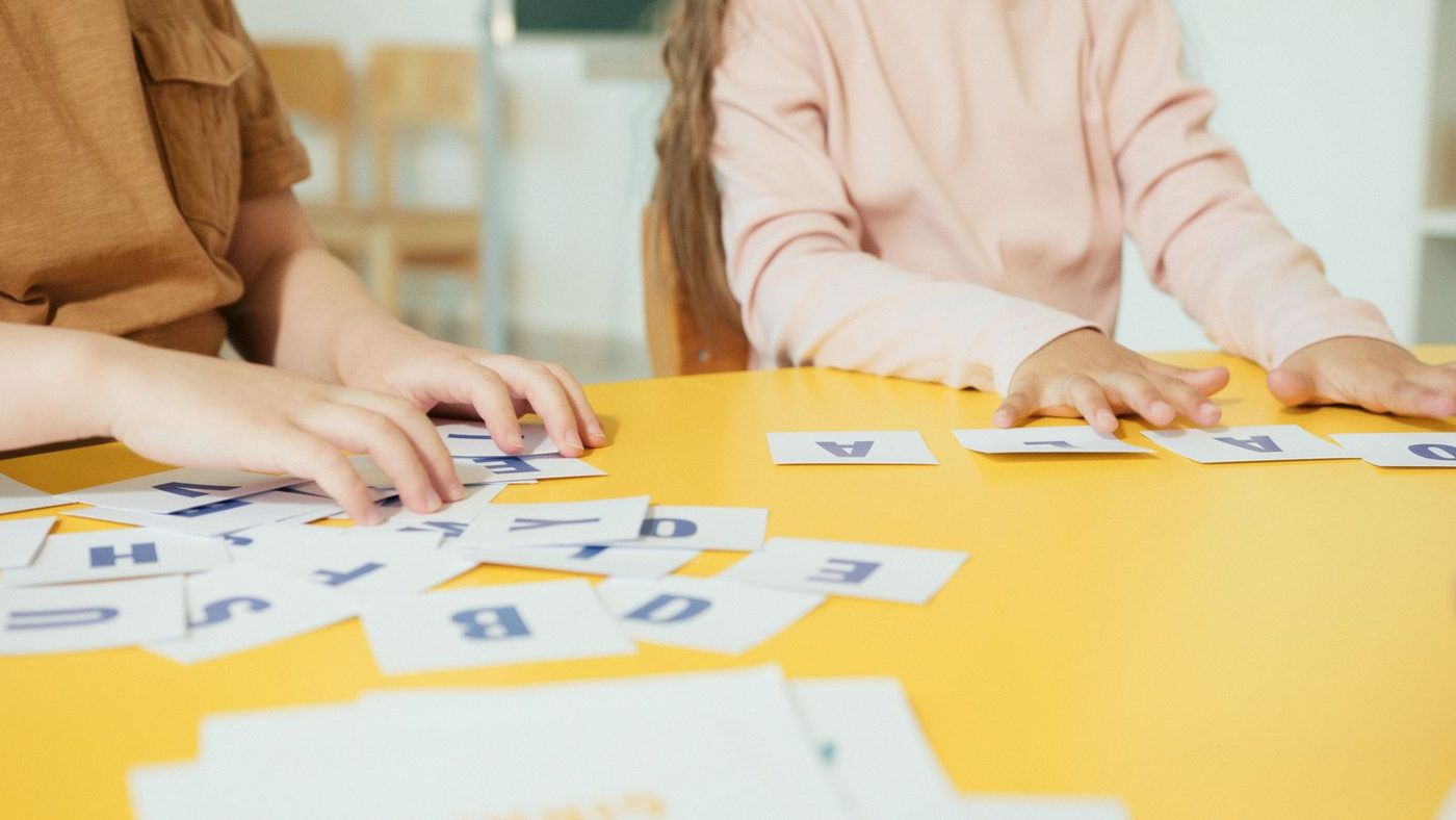 Mains d'enfants qui déplacent des cartes de lettres sur une table
