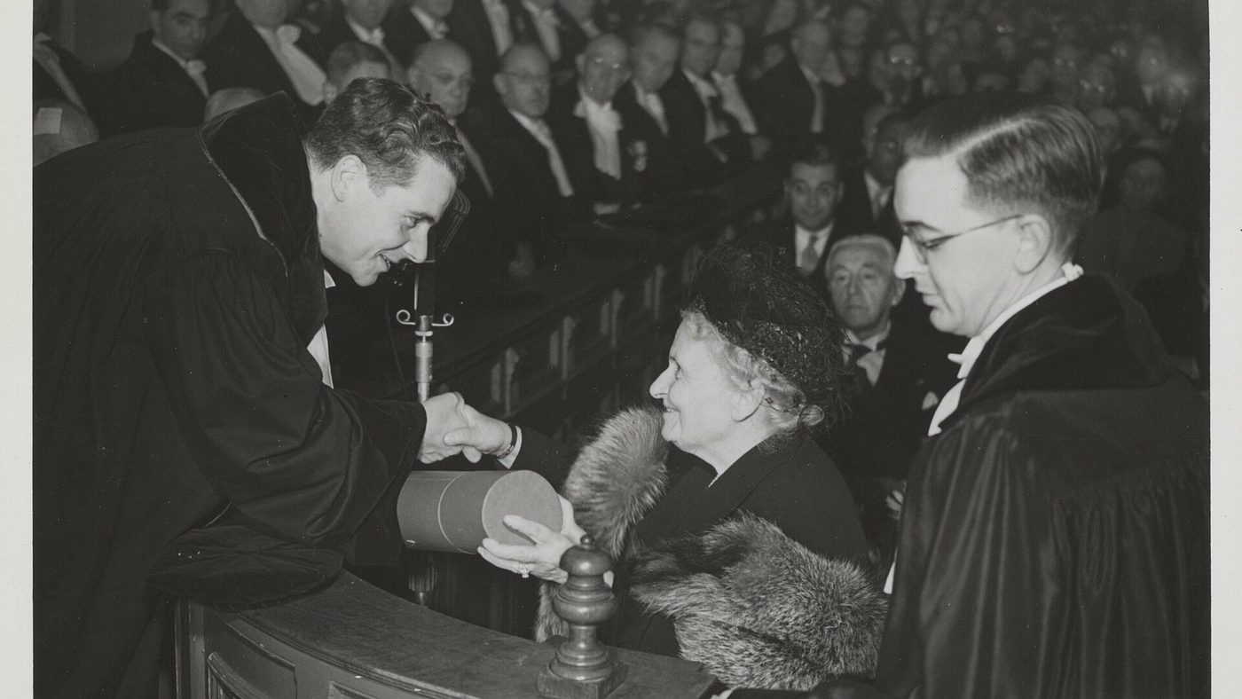 Maria Montessori reçoit un doctorat honoris causa des mains d'un universitaire en toge, Amsterdam, 1950