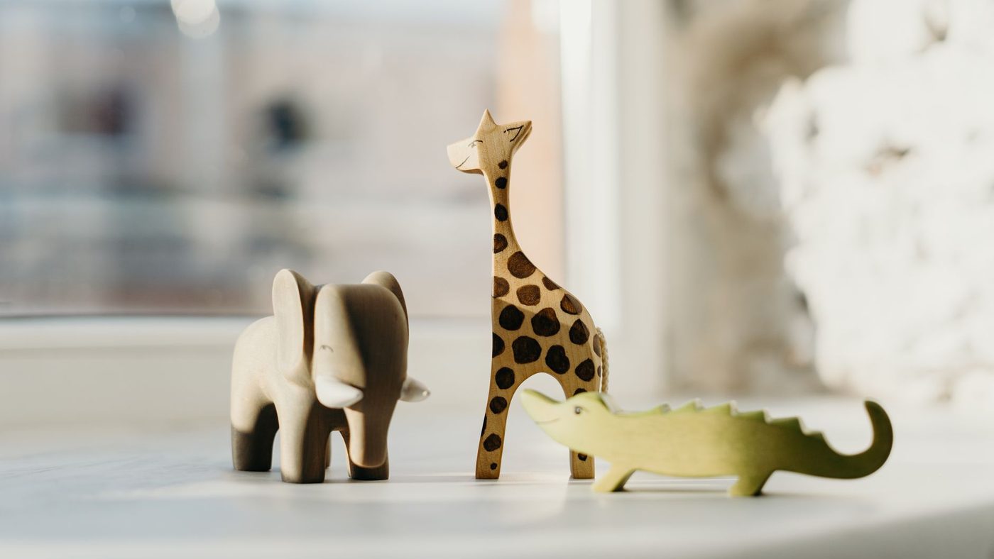 Des animaux en bois posés sur une table, un éléphant, une girafe et un crocodile