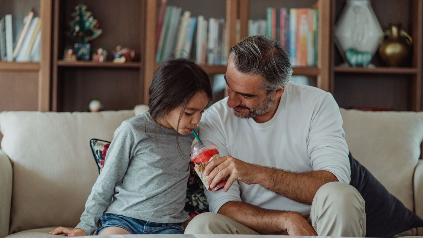 Un père et sa fille assis ensemble sur un canapé, en train de discuter